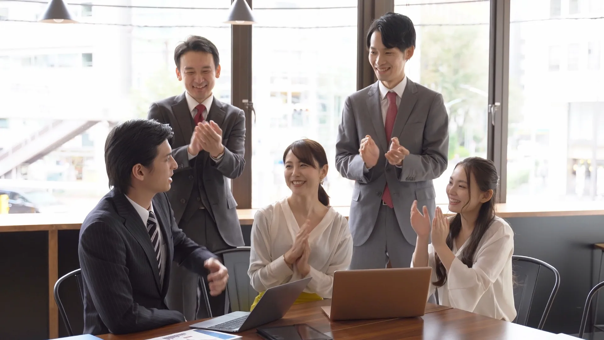 職場で笑顔で拍手をするビジネスパーソン、最適なパートナーと事業を加速