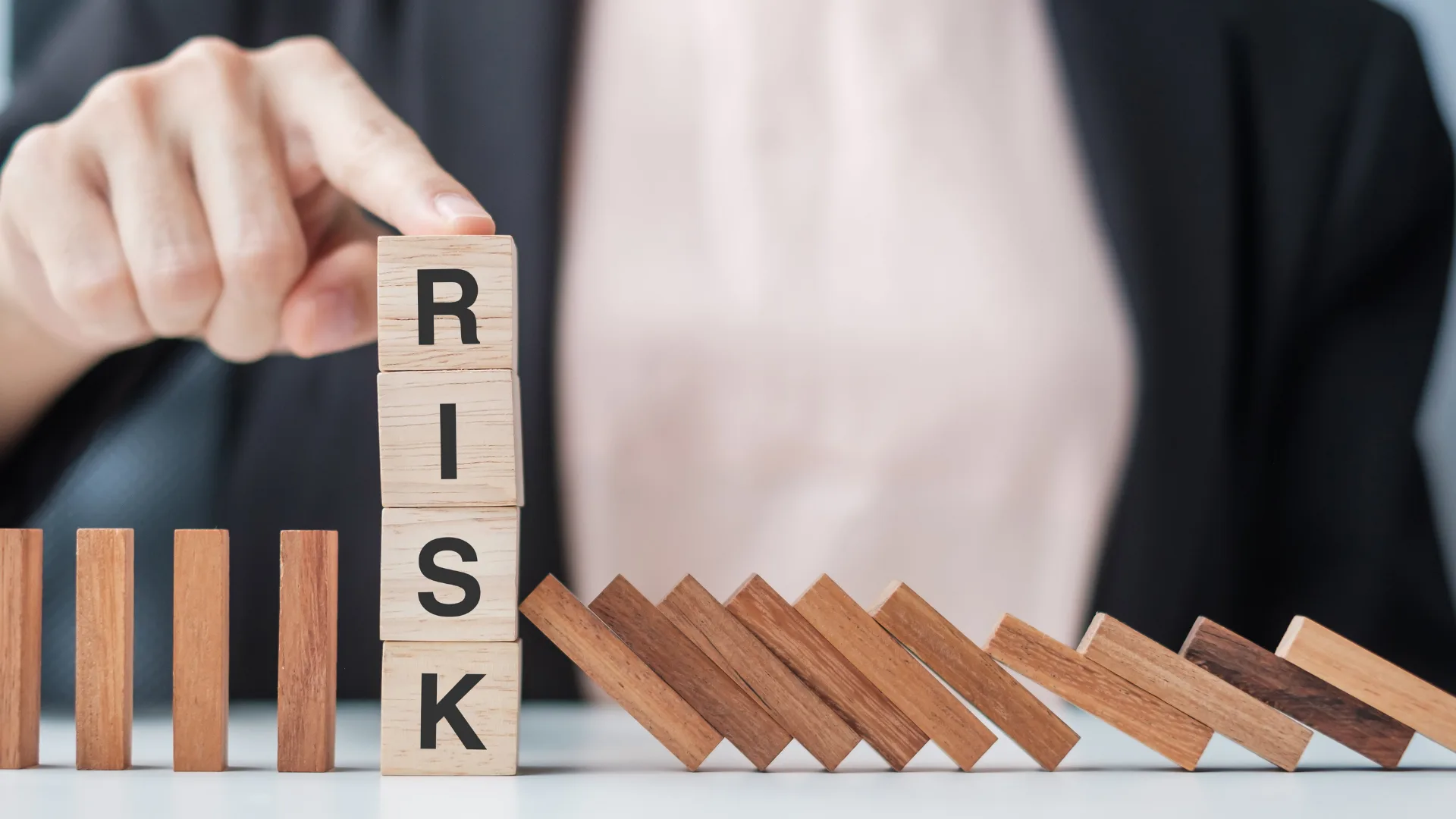 積み木の「RISK」が倒れるのを防ぐ、リスク回避のイメージ。