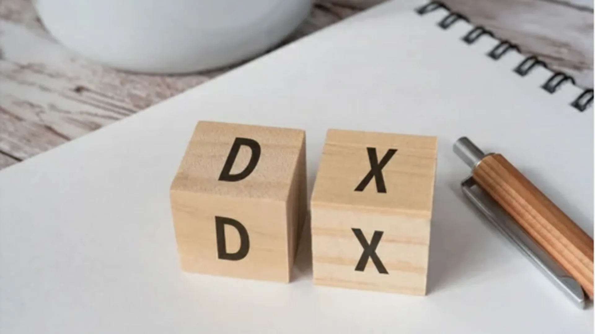DX（デジタルトランスフォーメーション）と書かれた木製ブロックとペン、変革を示すビジネスイメージ