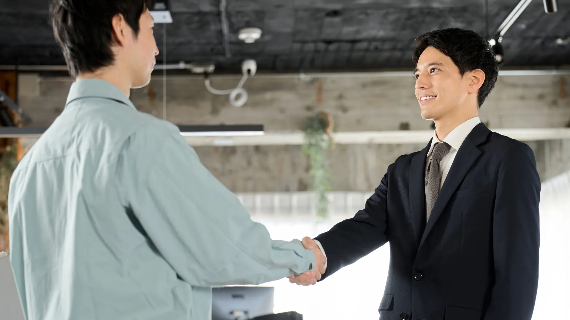 製造業の現場担当者と経営層が握手し連携を深める様子、DXへの取り組み