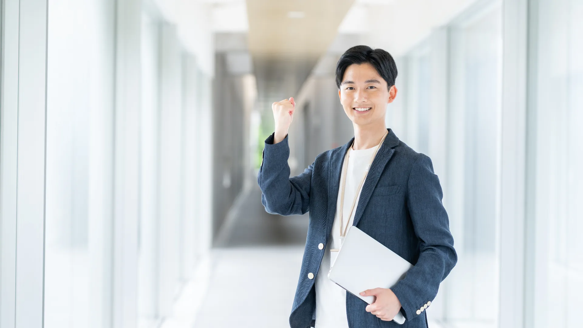 ノートPCを持ちガッツポーズをする笑顔の男性社員