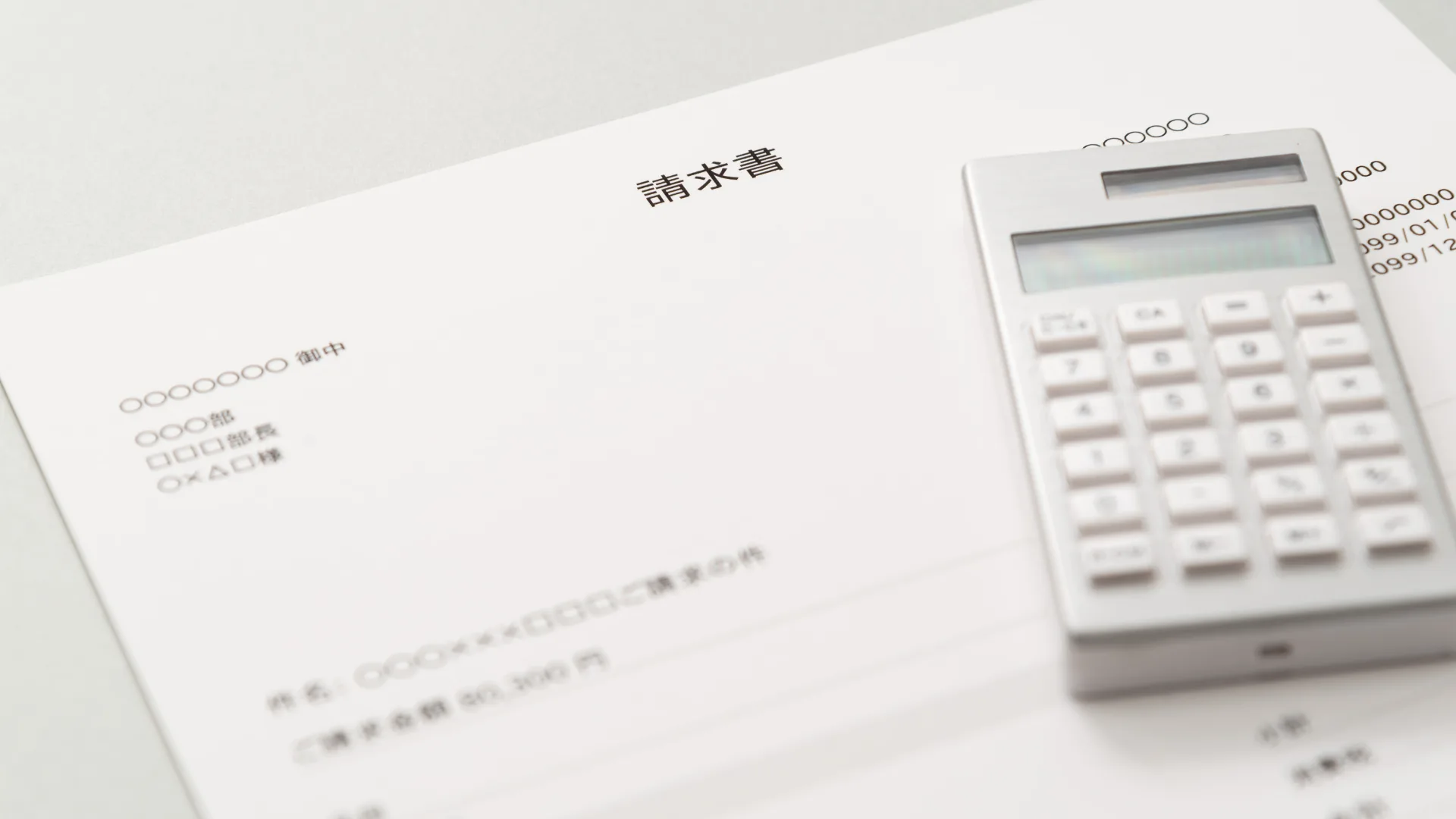 請求書と電卓が置かれた、経理・事務作業のイメージ。