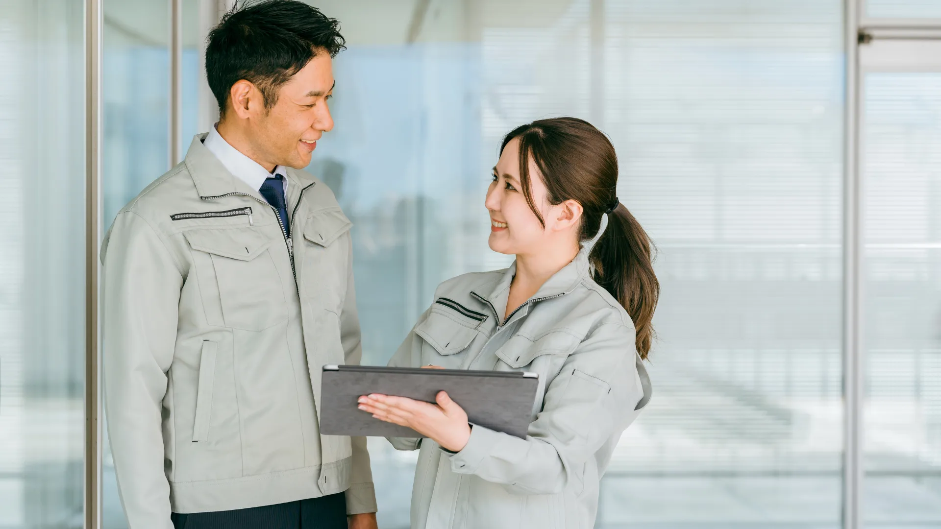 作業服の男女がタブレットを見ながら笑顔で会話、最終的なまとめ