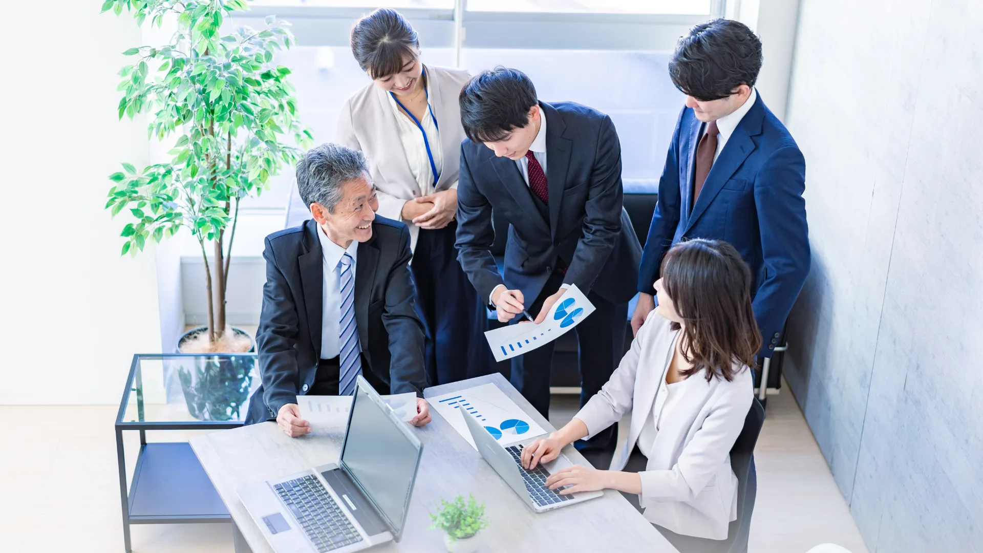 オフィスで資料を見ながら話し合う複数のビジネスパーソン