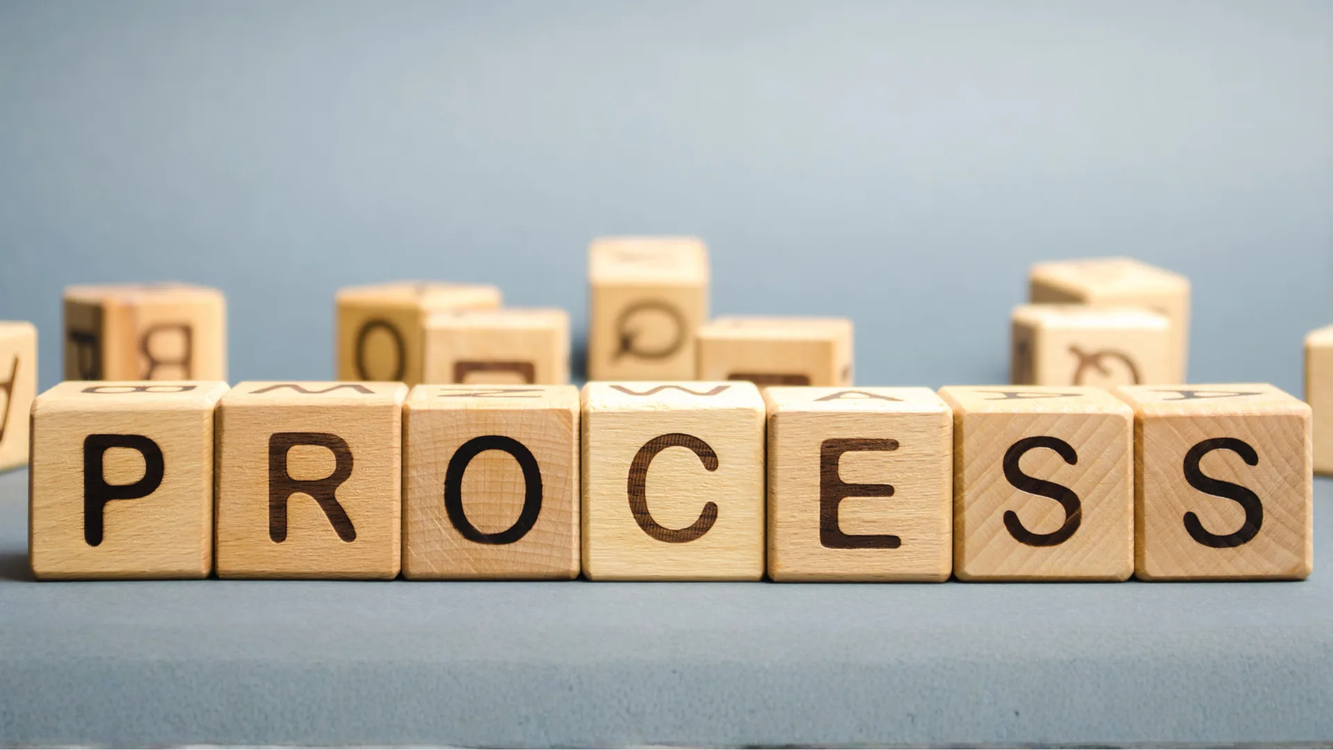 「PROCESS」と書かれた木製の文字ブロックが並ぶ様子