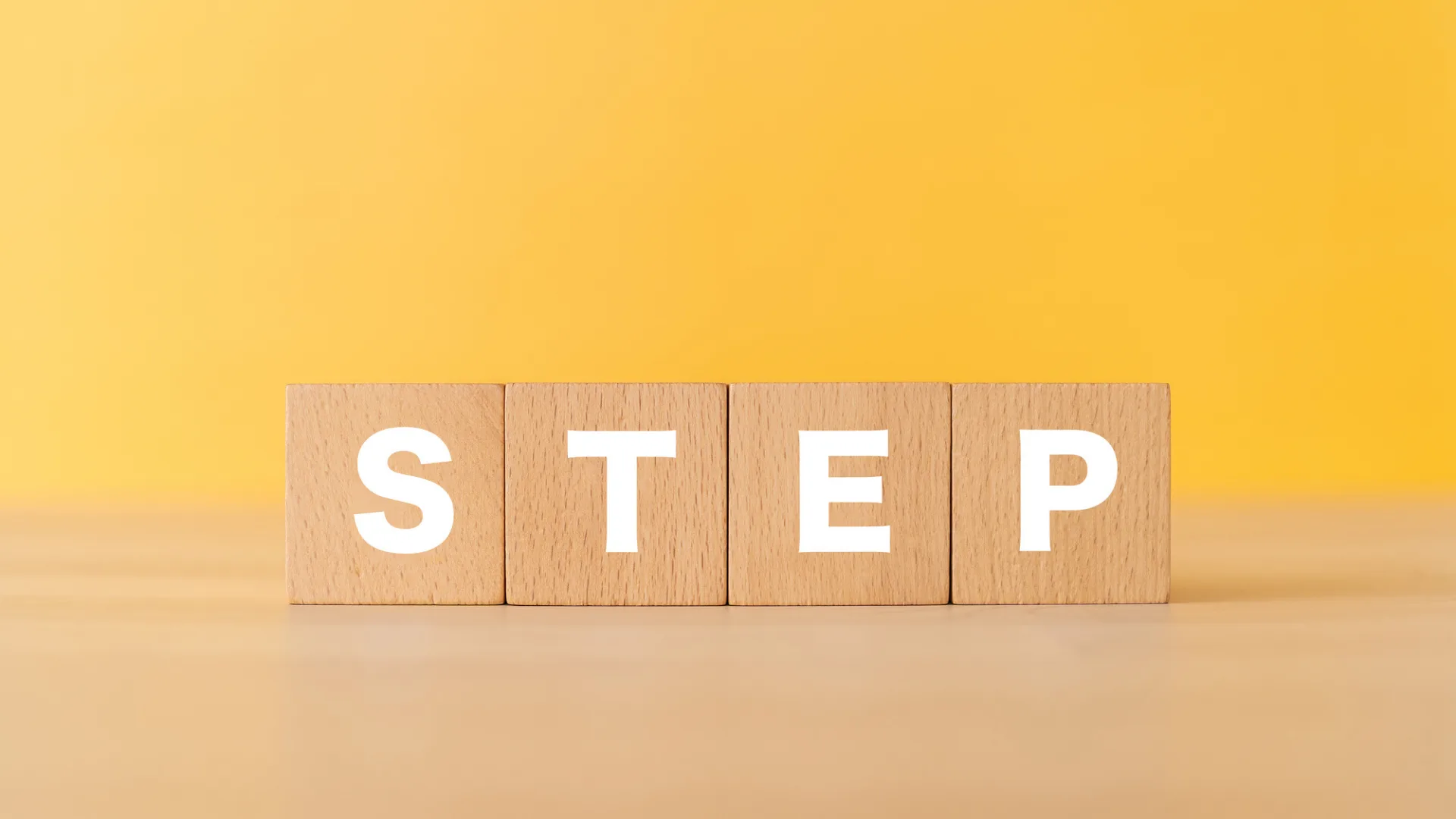  黄色の背景に、「STEP」と書かれた木製ブロック。
