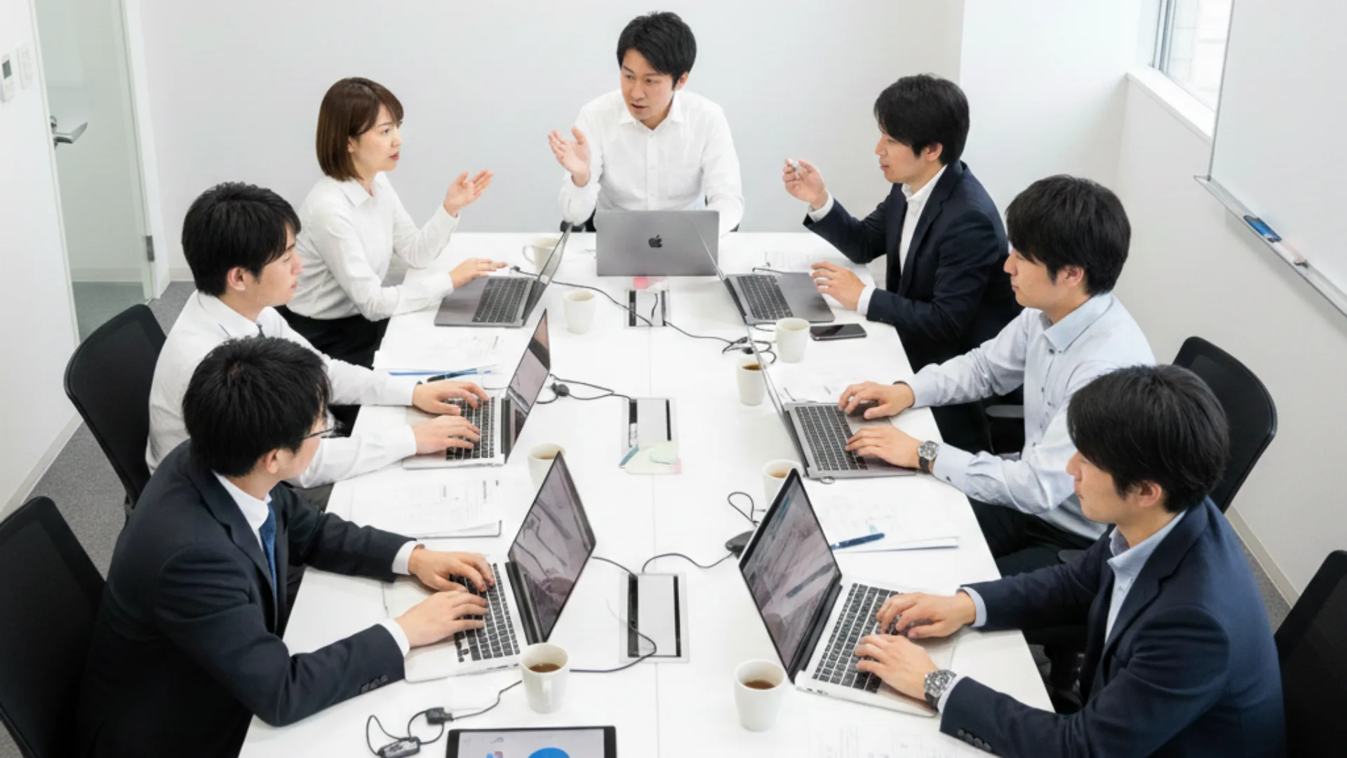 会議室でノートパソコンを開き議論するチーム、労働生産性向上のメリット
