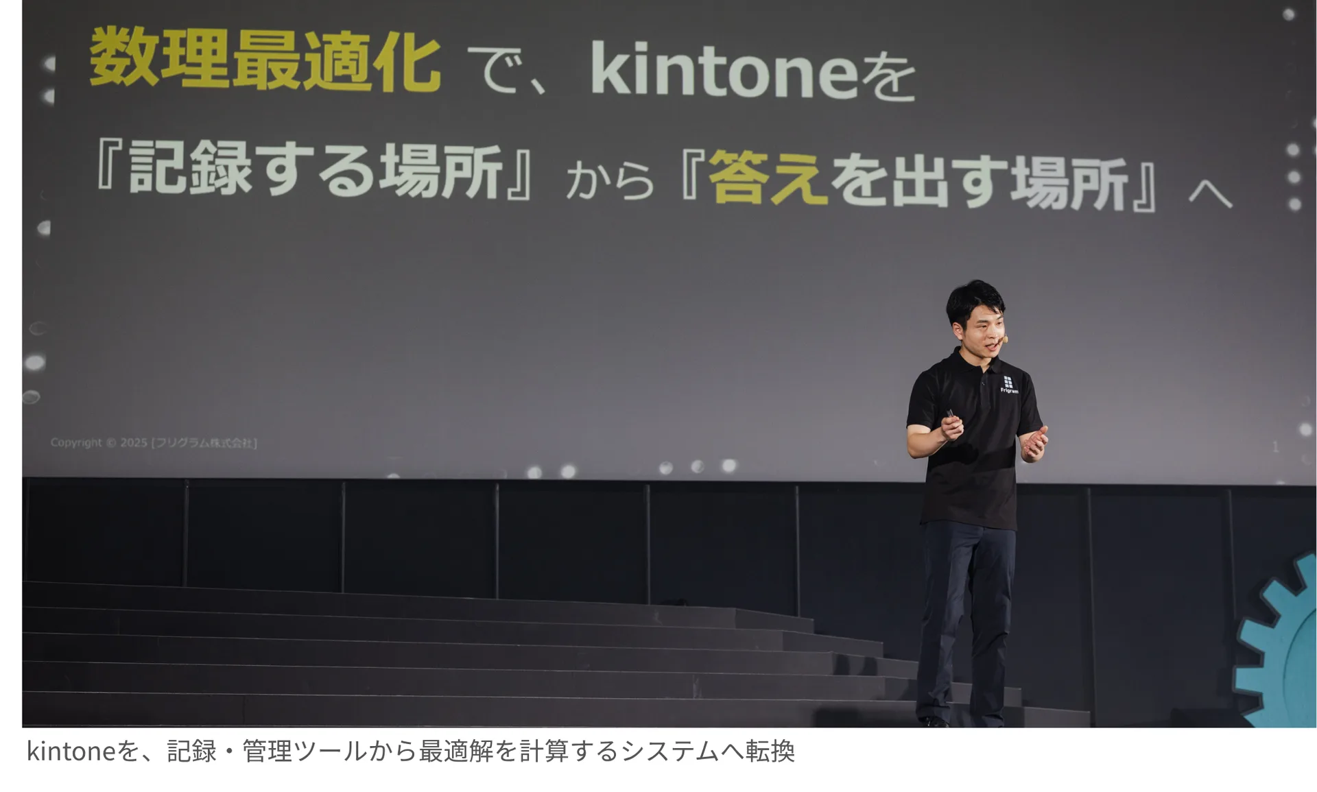 「数理最適化で、kintoneを『記録する場所』から『答えを出す場所』へ」のスライドの前でプレゼンする宮下。