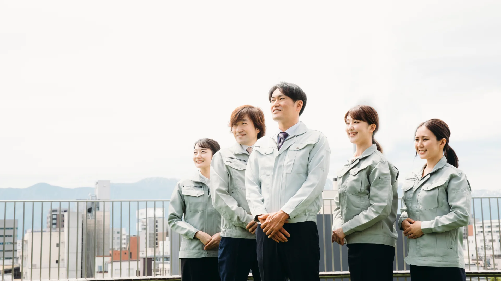 屋上で作業着を着た5人の企業のチーム。労働分配率は価値創造能力と従業員還元のバランスを測るコンパス
