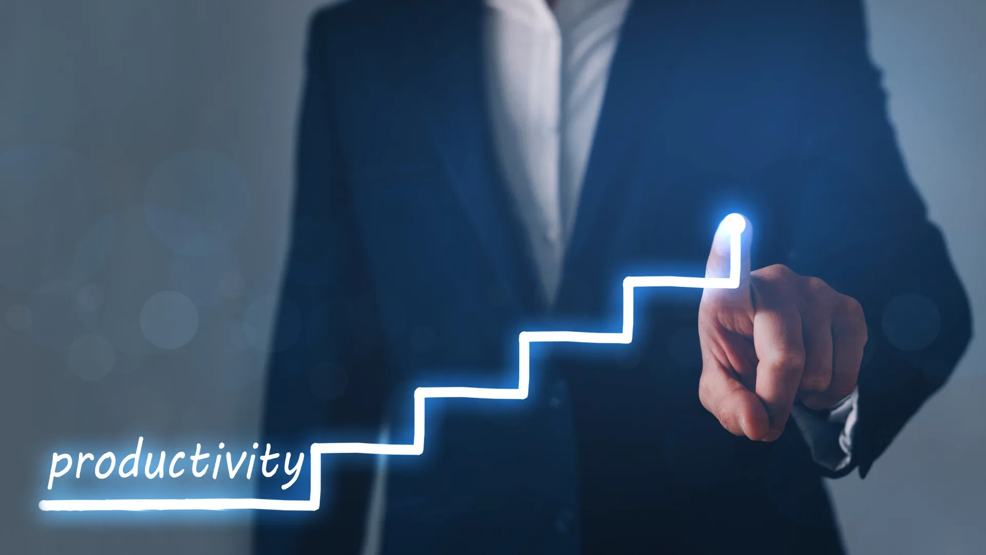 「productivity」の文字と階段状に上昇するグラフを指さすビジネスパーソン