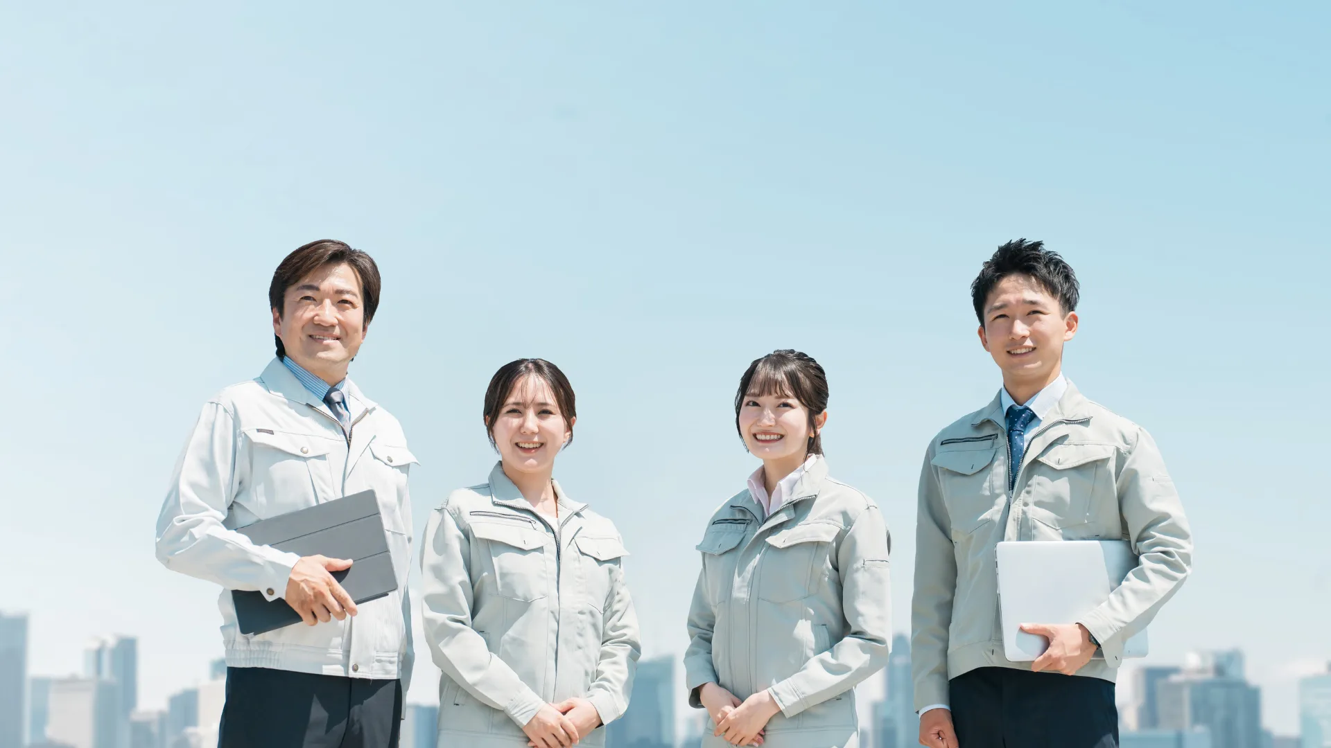 青空の下でスマートファクトリーの未来を見据えて笑顔で並ぶ製造業のチーム