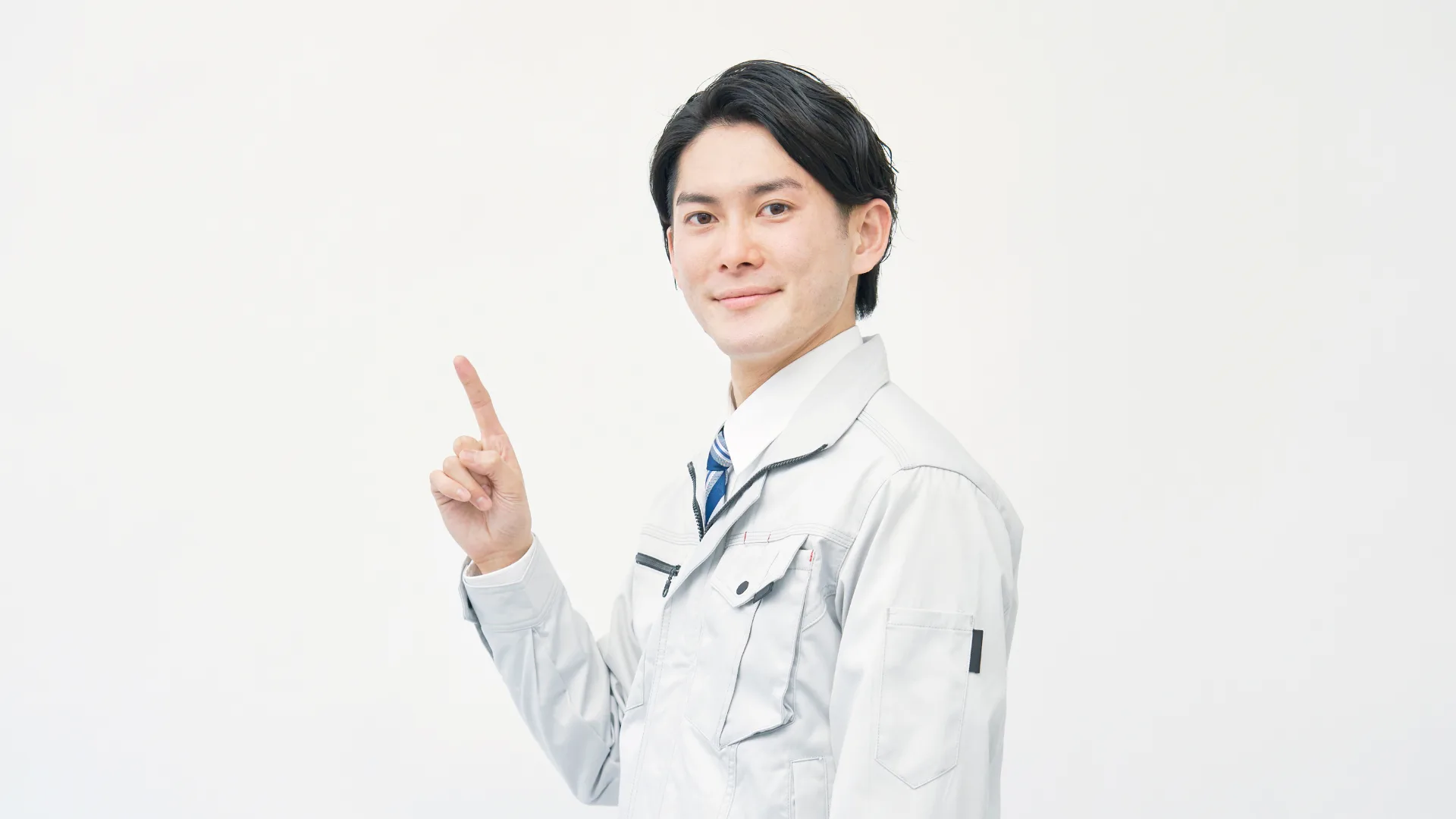 作業服を着て笑顔で指差しをする男性の上半身